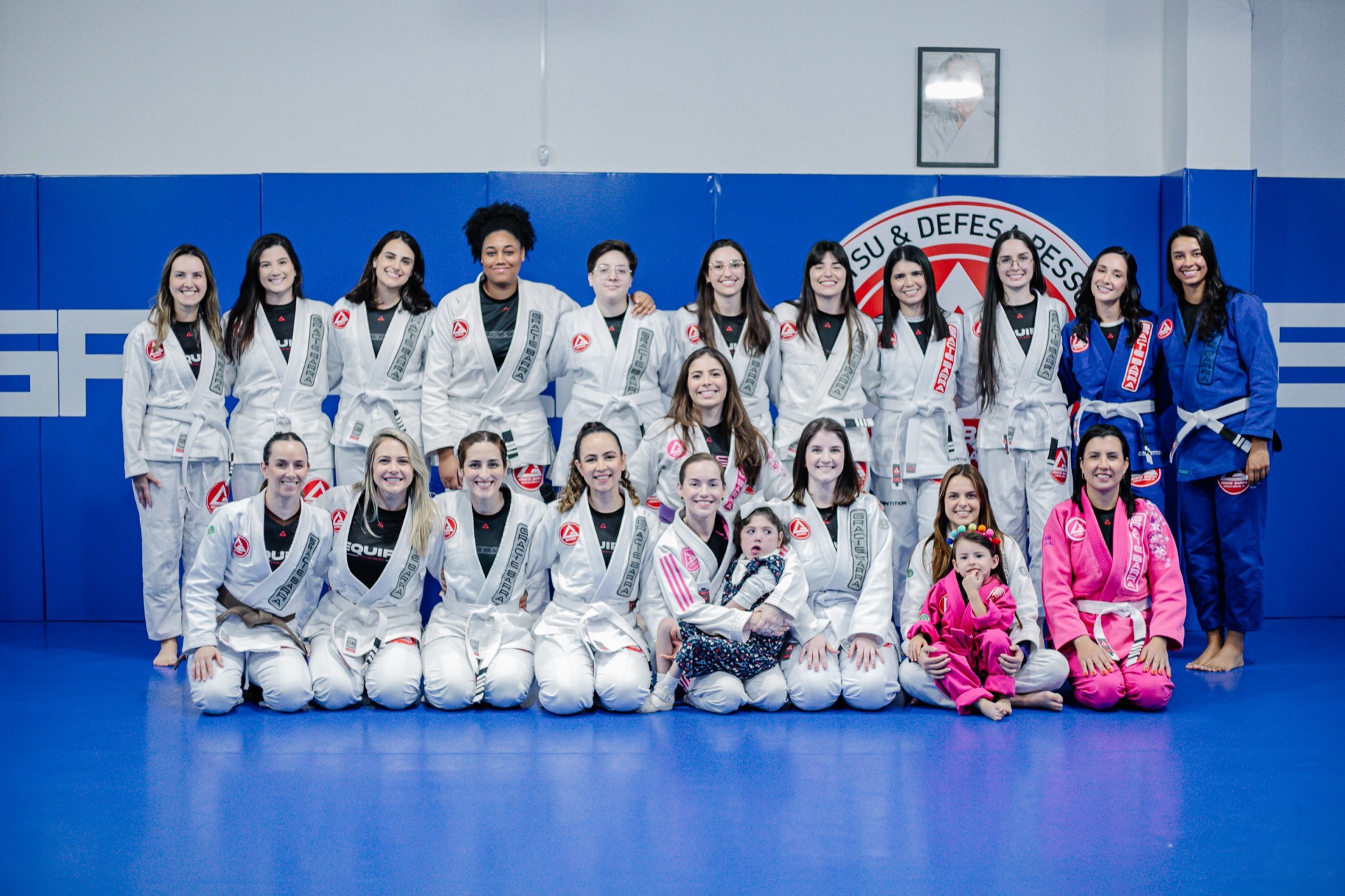 Turma feminina da Gracie Barra Tubarão reunida no tatame, alunas de kimono e faixas variadas